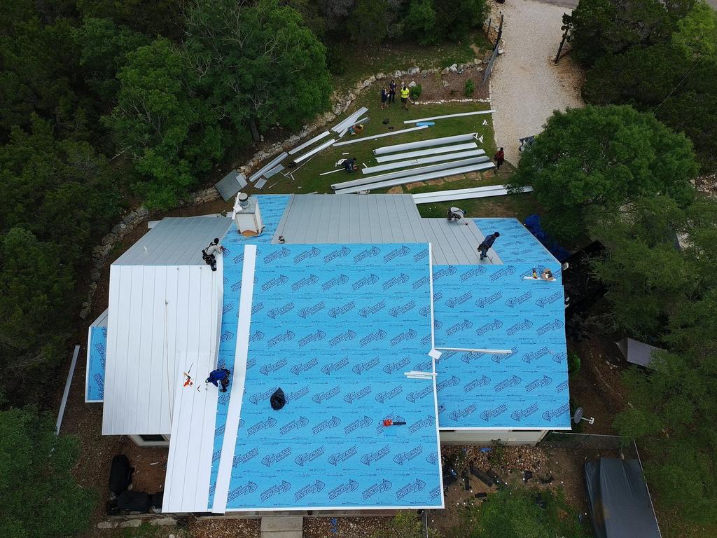 Standing seam install in progress — synthetic underlayment and panels staged