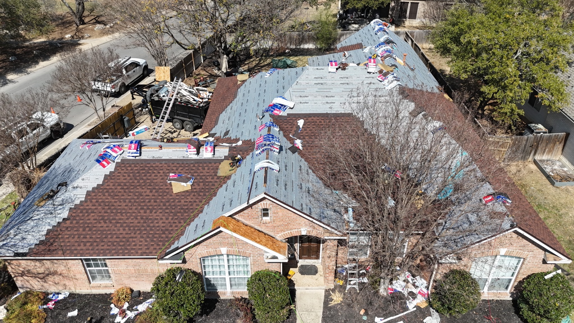 Front aerial of Helotes roof replacement showing staging, underlayment, and shingle progress