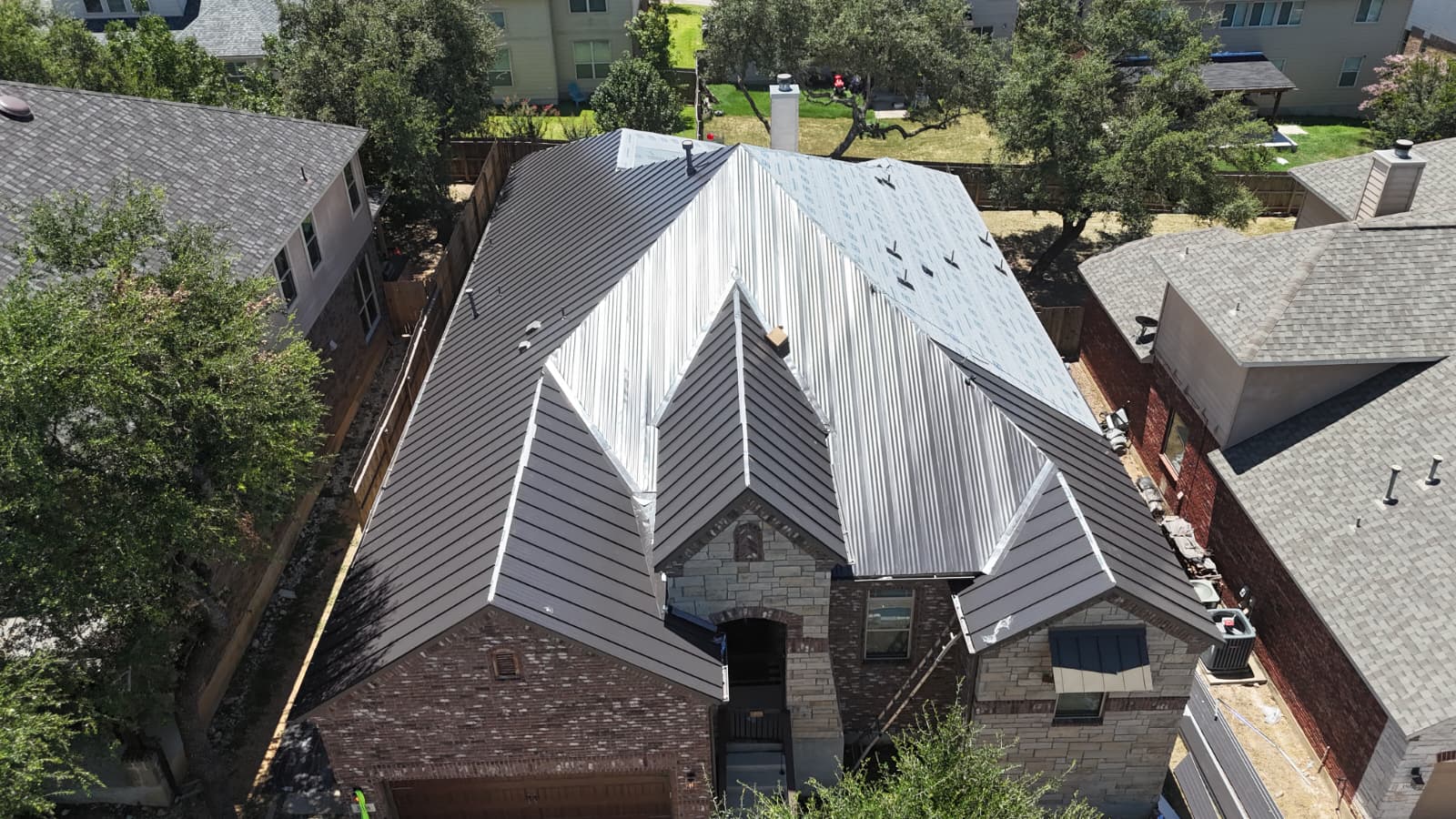 Front aerial of completed charcoal standing seam metal roof on San Antonio home