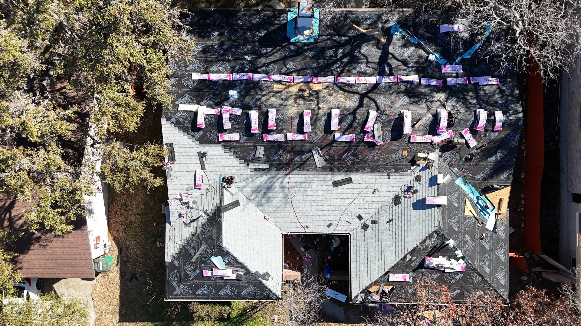 Tear-off in progress with Owens Corning shingle bundles staged across the roof