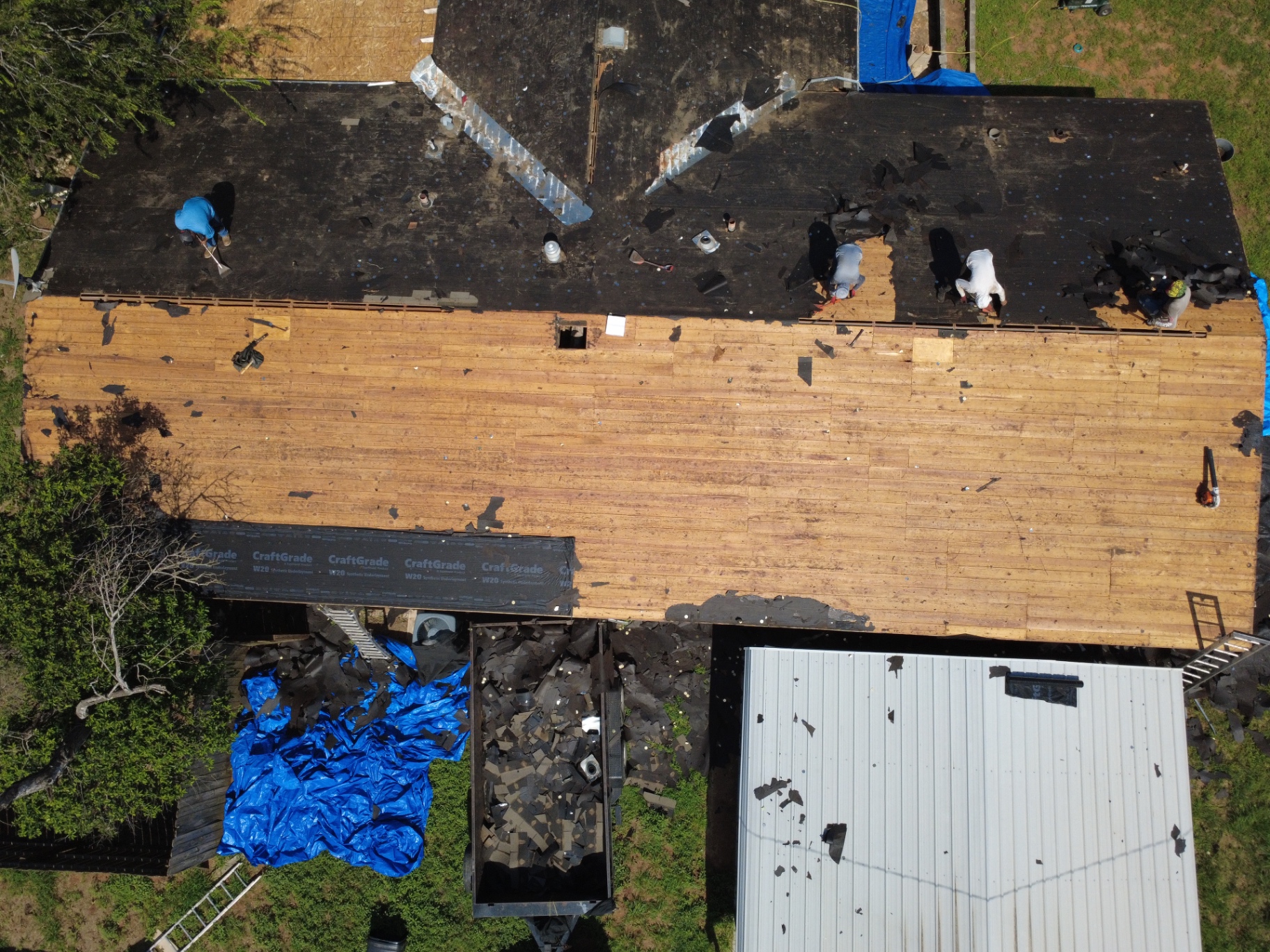 Top-down aerial of Pearsall roof tear-off with exposed decking and remaining old underlayment