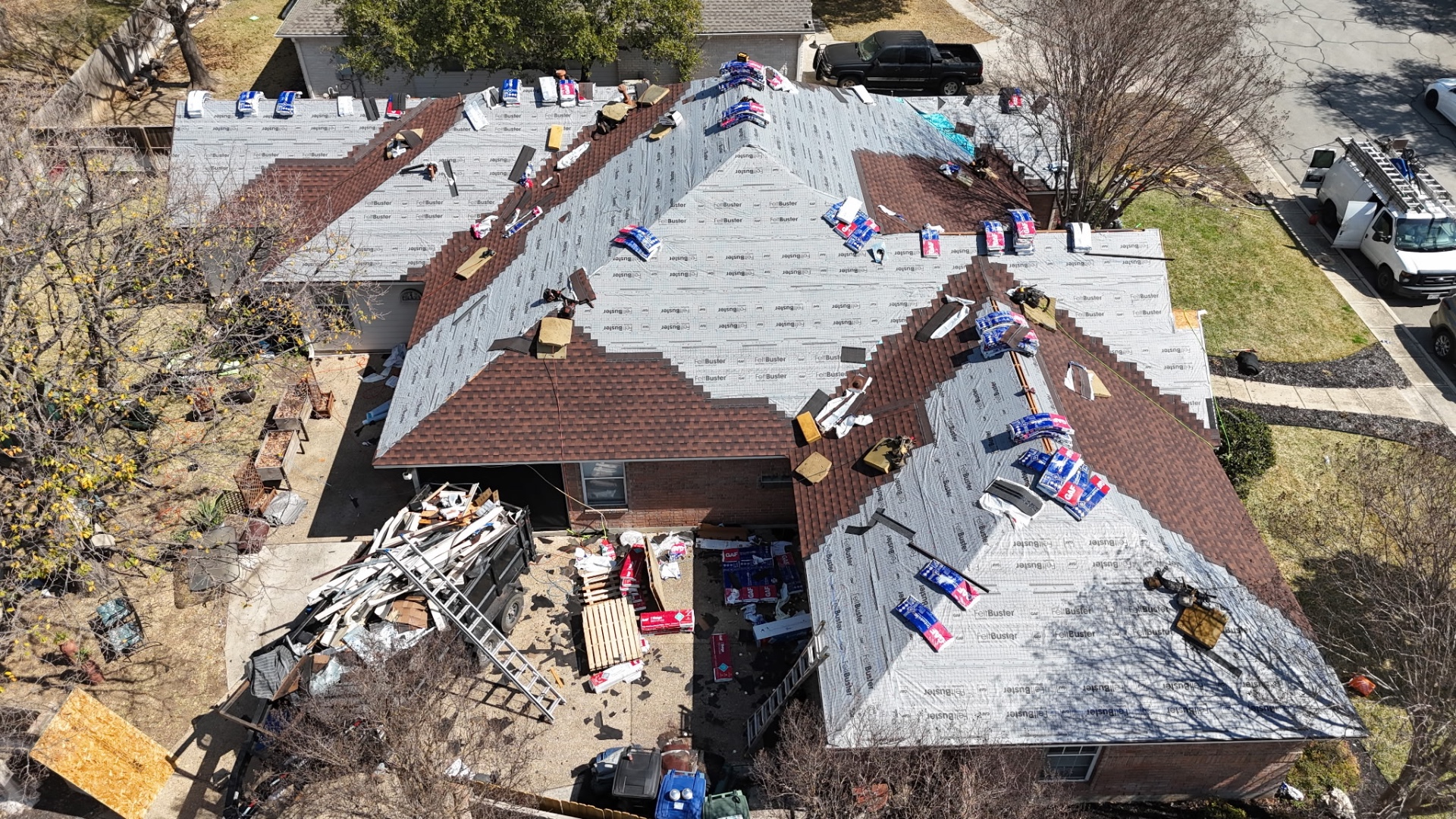 Angled drone view of Helotes roof replacement showing underlayment and shingle installation progress