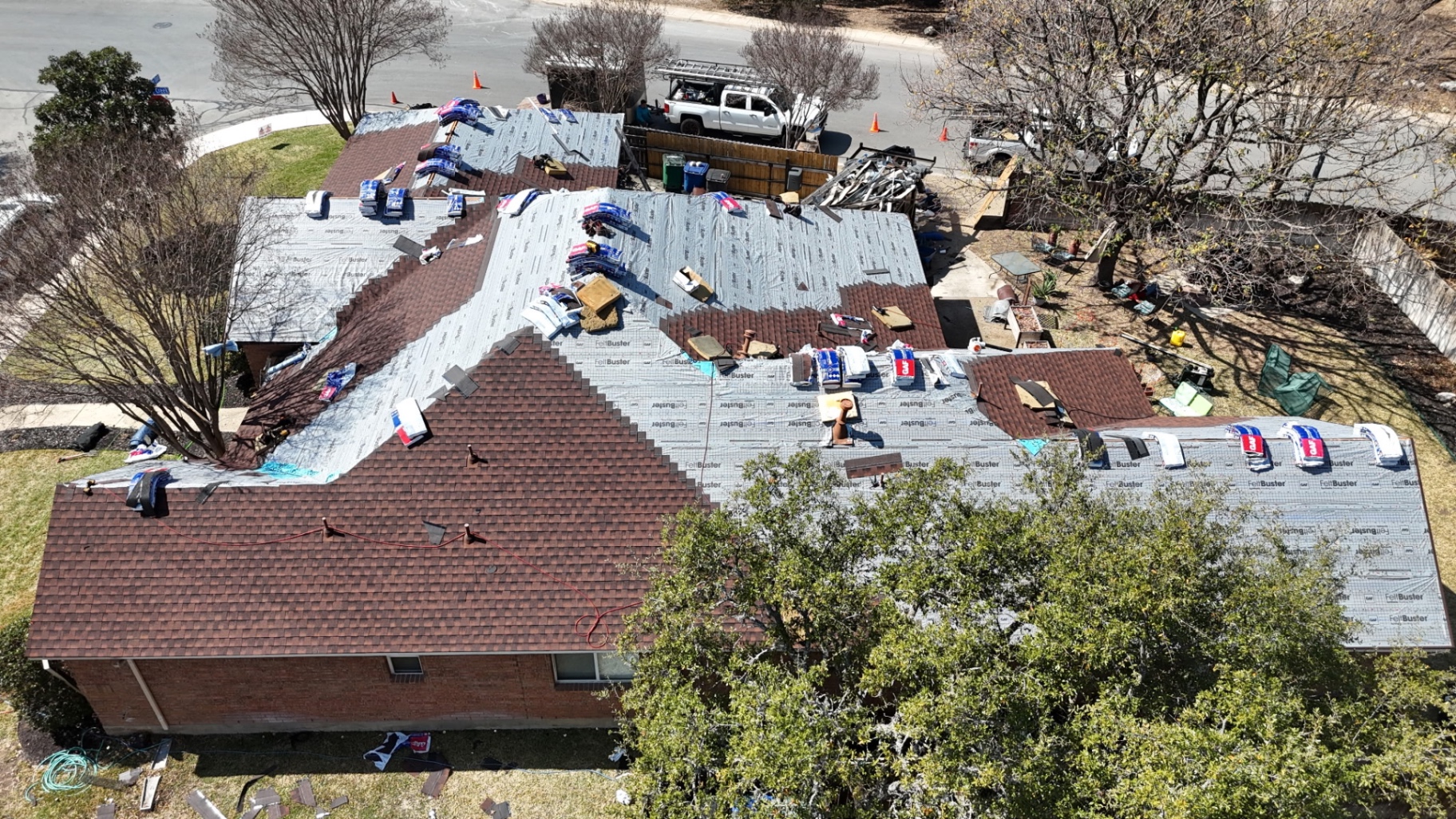 High drone view of Helotes roof replacement with multiple slopes underlaymented and partially shingled
