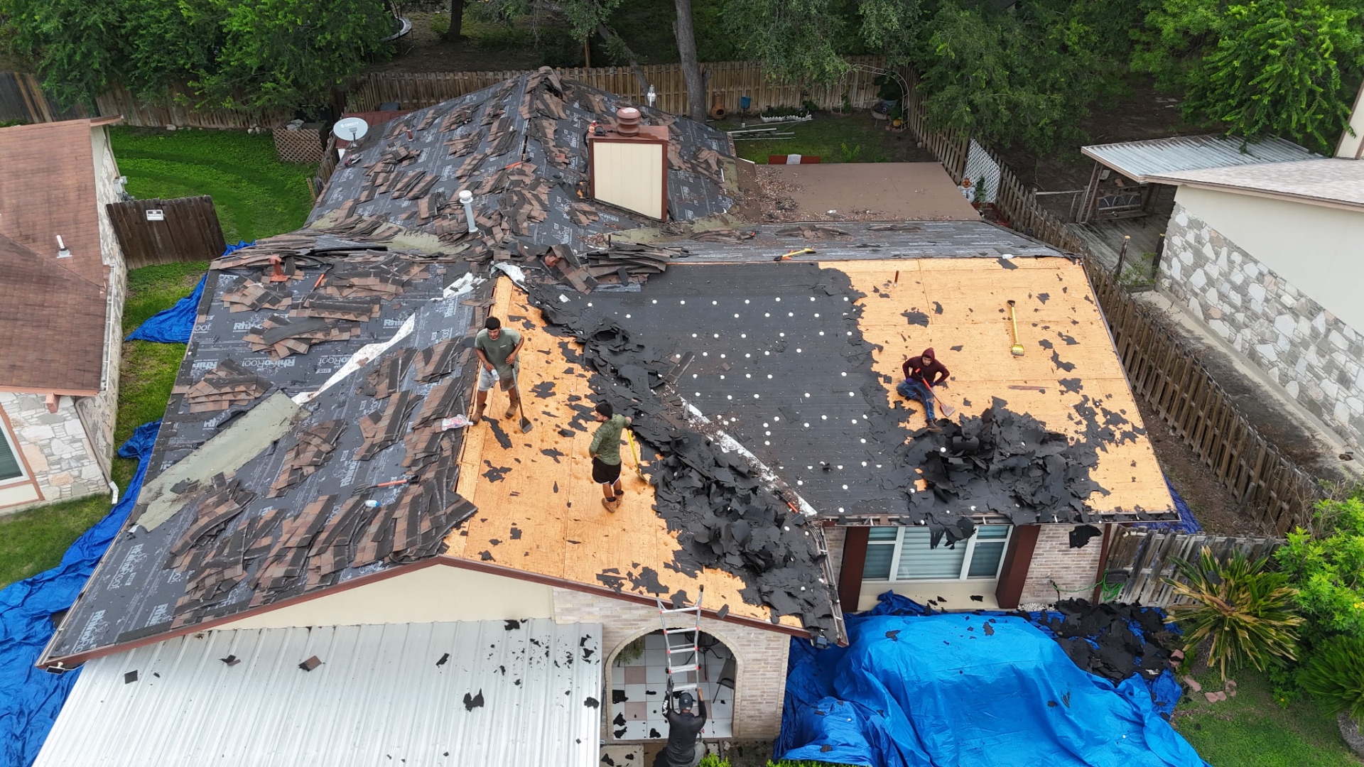 Crew tearing off old shingles and felt on a San Antonio home