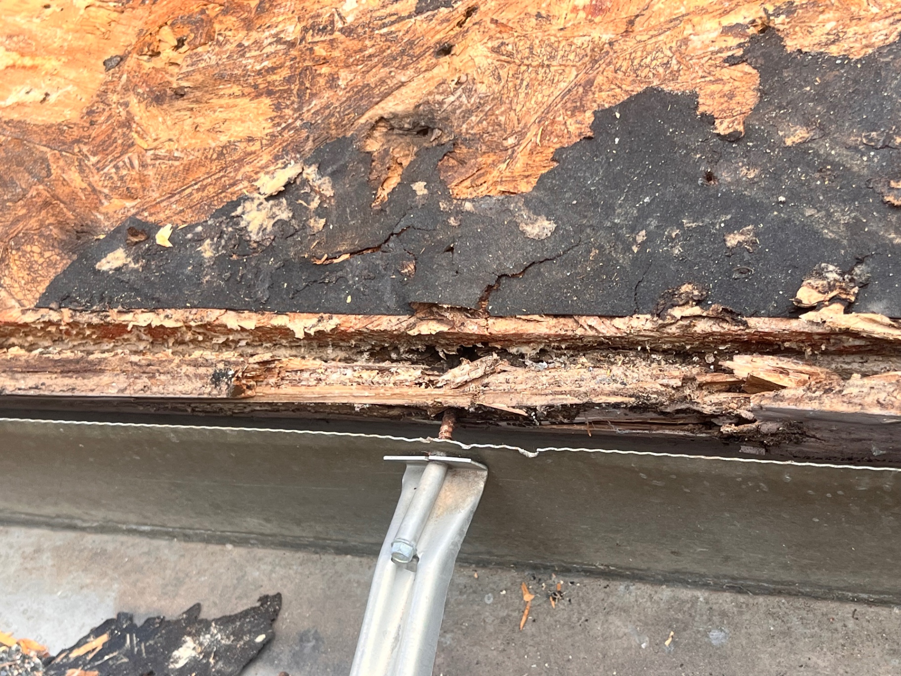 Rotten roof decking exposed at the eave during Braun Station roof tear-off in San Antonio