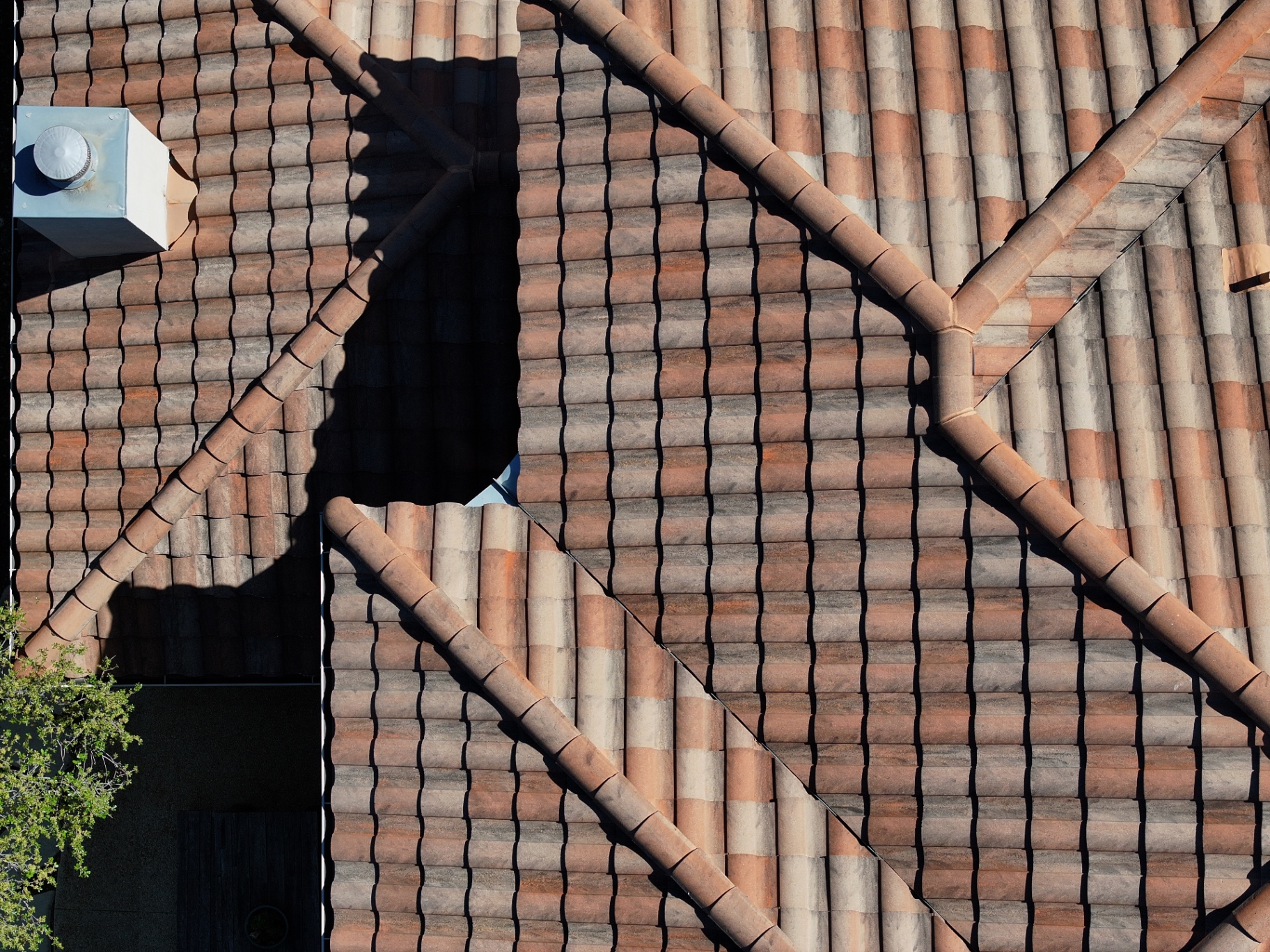 Drone detail of intersecting ridges and repaired concrete tiles on Boerne home