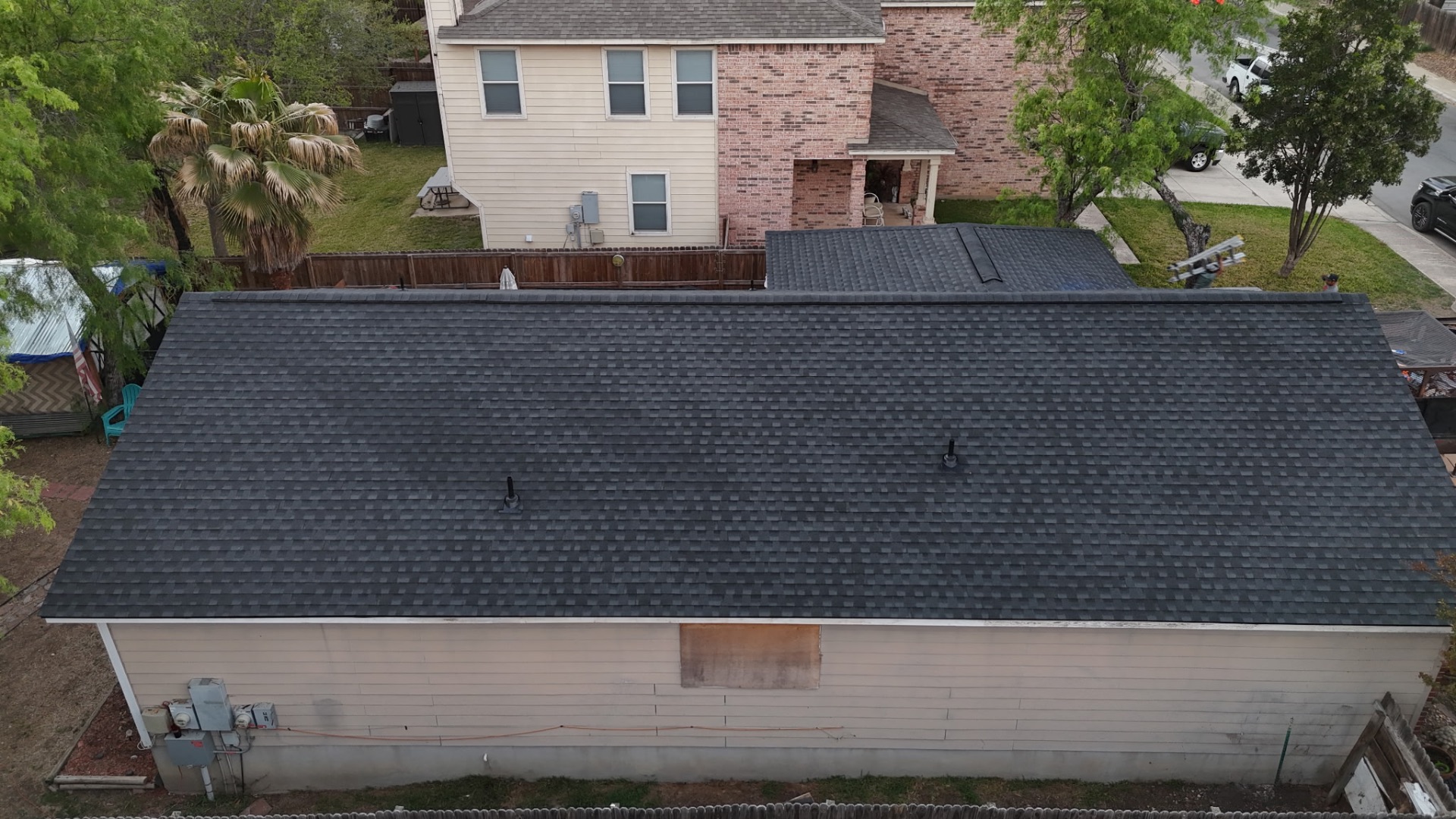 Finished rear elevation showing completed charcoal shingle roof on West Side San Antonio home