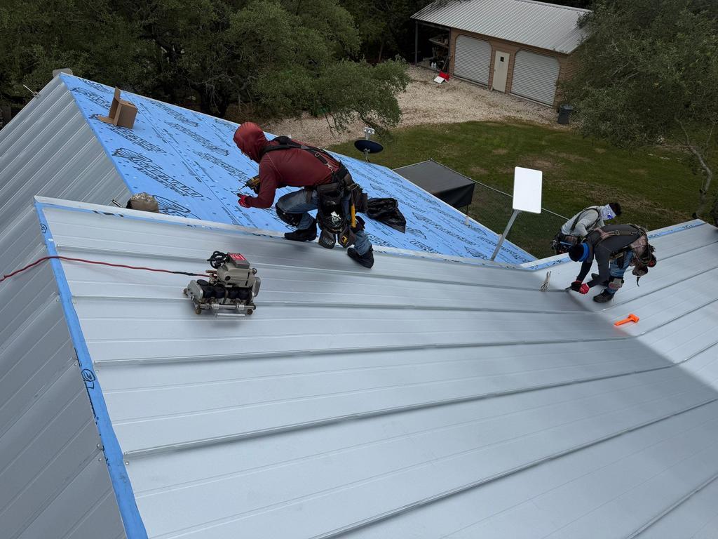 Crew seaming standing seam panels on a Spring Branch home